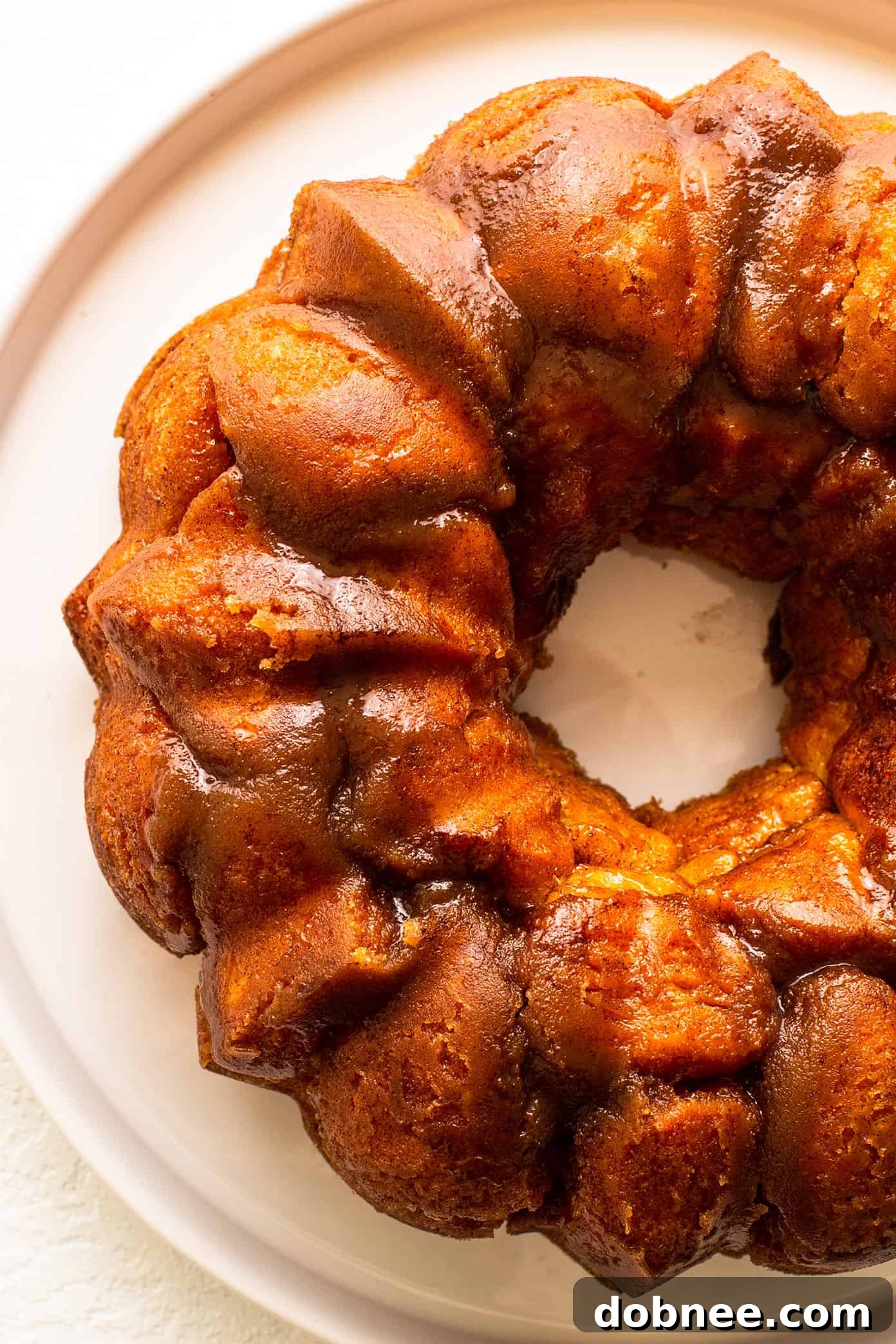 A slice of warm monkey bread being pulled apart, showing the gooey cinnamon sugar layers