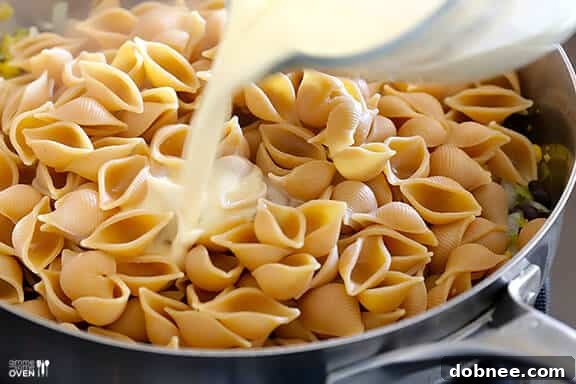 Pasta and veggies combined in a pan for Mexican Mac and Cheese