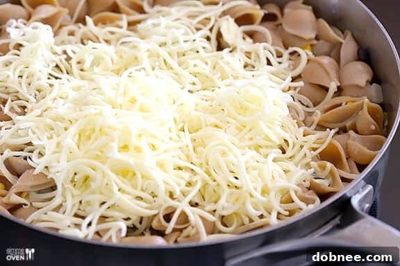 Adding shredded cheese to creamy pasta