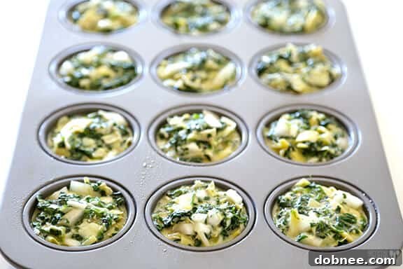 Portioning the Spinach Artichoke Quiche mixture into muffin cups.