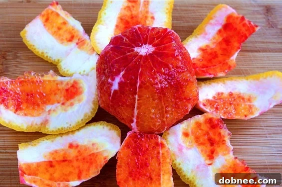 Close-up of the vibrant orange salad, showing the intricate layers of blood oranges, mandarin segments, fresh greens, and crumbled cheese.