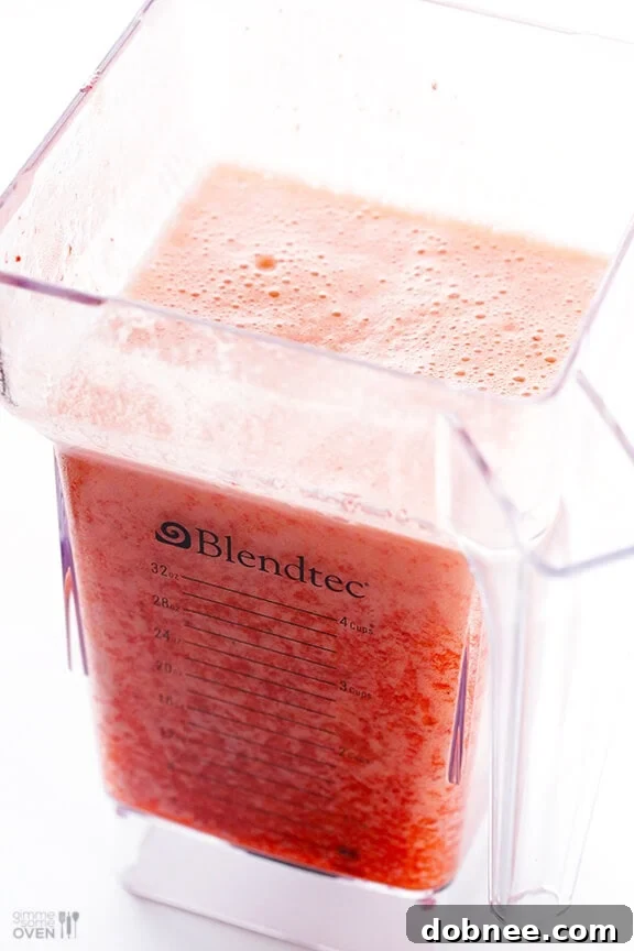 Ingredients being added to a blender for a fresh strawberry margarita.
