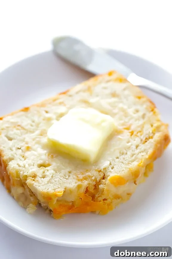 Sliced Garlic Cheddar Beer Bread on a wooden board, invitingly served with a spread of butter.