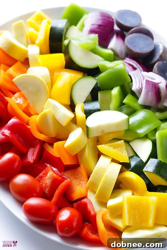 Assortment of fresh vegetables including zucchini, tomatoes, onions, and purple potatoes for skewers