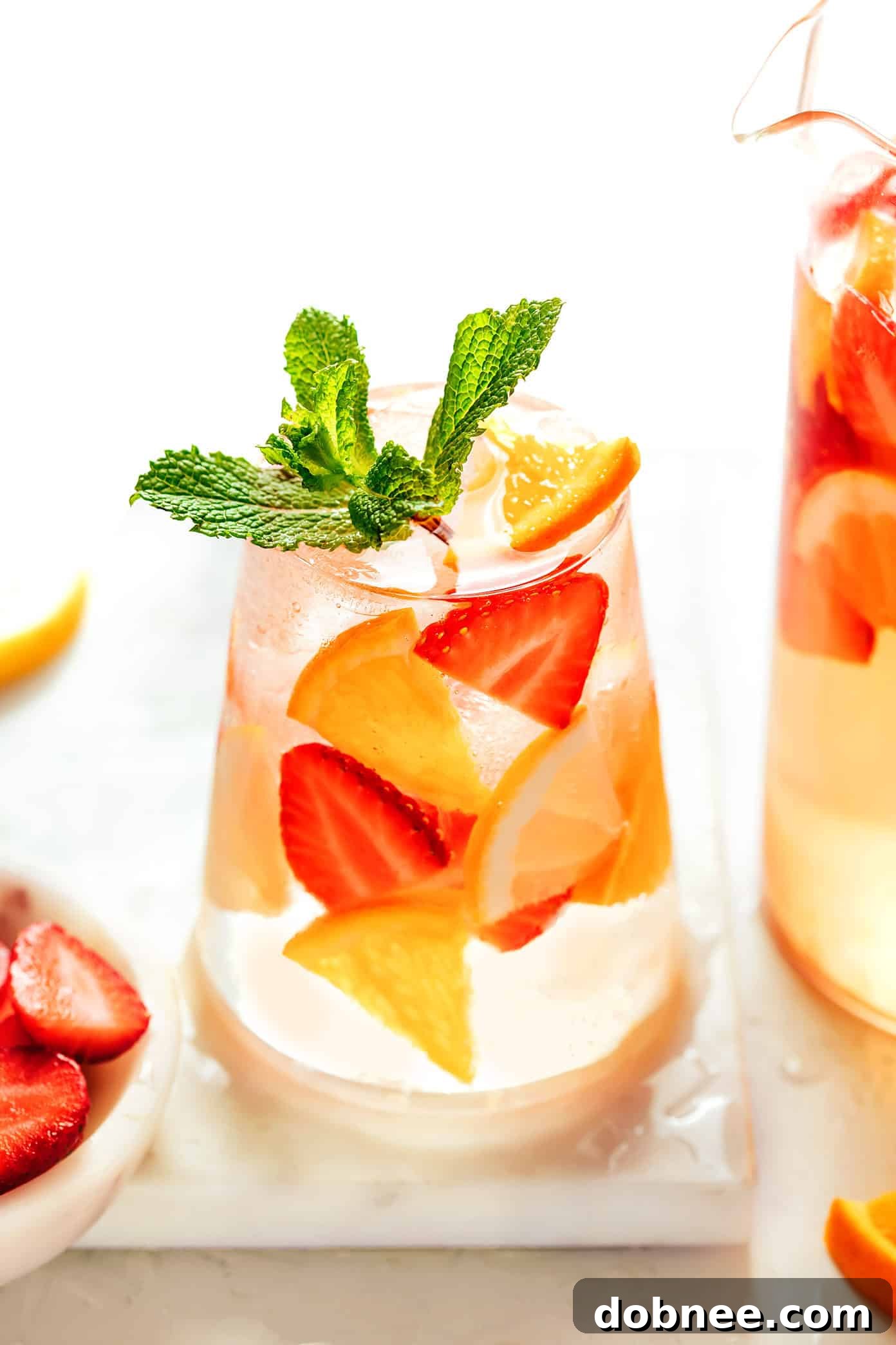 strawberry sangria in a glass and pitcher on an outdoor table