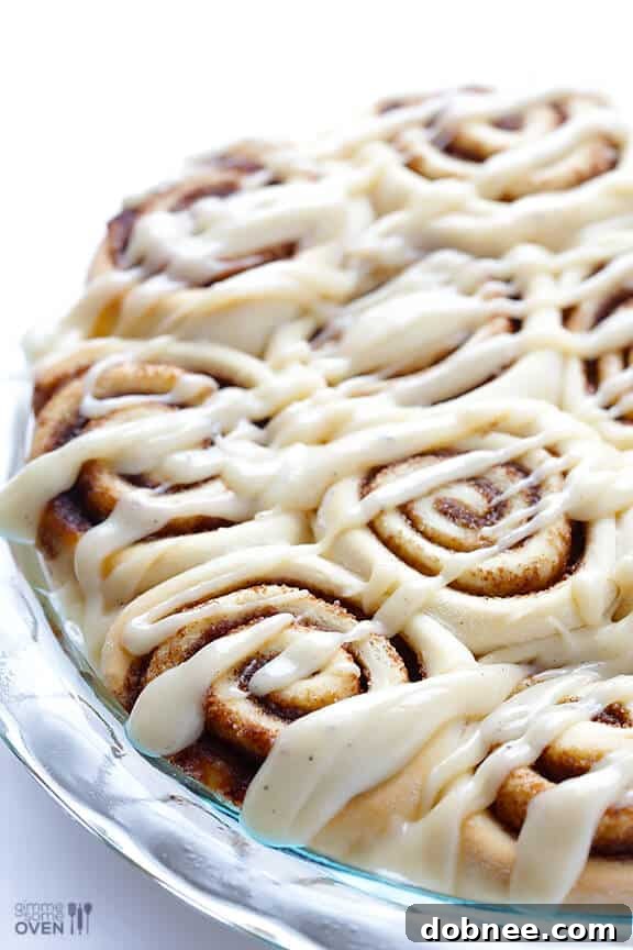 Generously drizzling rich brown butter cream cheese frosting over warm cinnamon rolls.