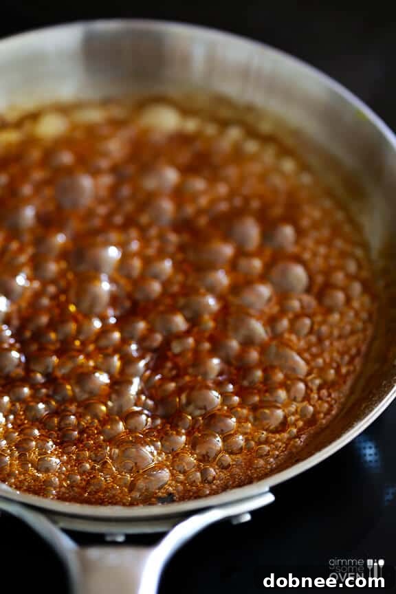 Pineapple rings soaking in the rum, brown sugar, and cinnamon marinade in a glass baking dish.