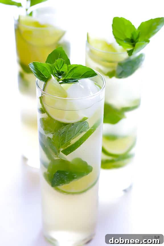 Hands muddling fresh mint and lime slices in a glass for a Ginger Beer Mojito.