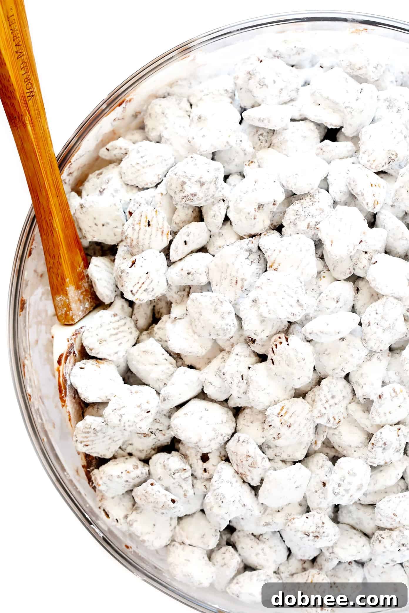 Classic Puppy Chow (Muddy Buddies) piled high on a white serving tray, ready to be enjoyed.