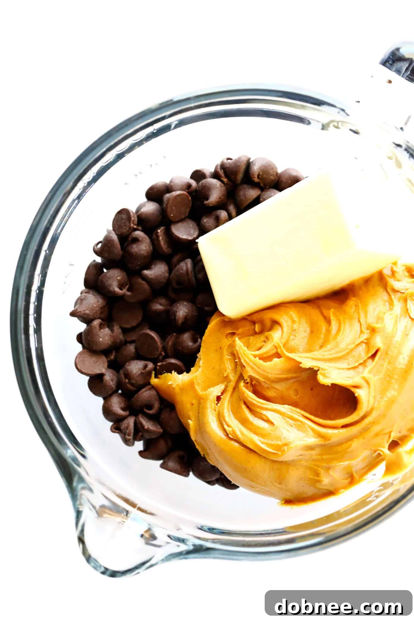 Close-up of melted chocolate, peanut butter, and butter being stirred until smooth in a microwave-safe bowl.
