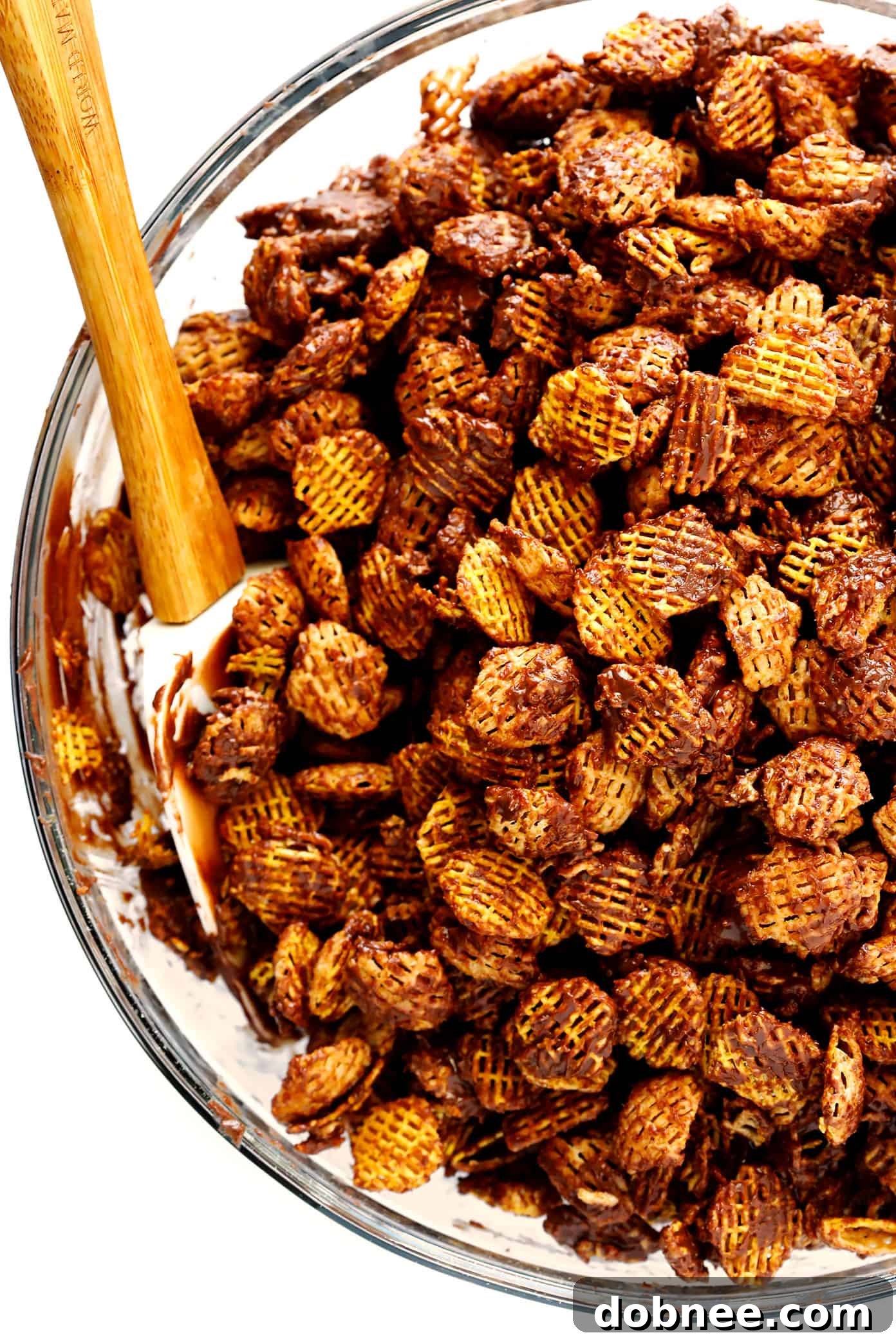 Chocolate-coated cereal being gently mixed in a large bowl, ensuring even coverage.