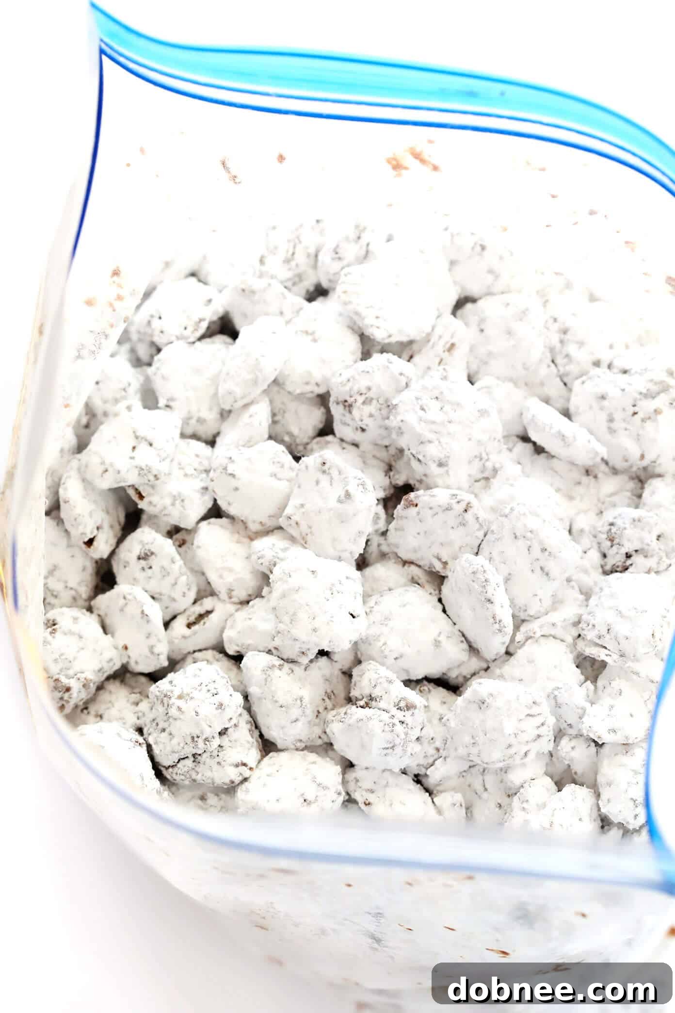 A large bowl filled with classic Puppy Chow (Muddy Buddies), perfectly coated in powdered sugar.