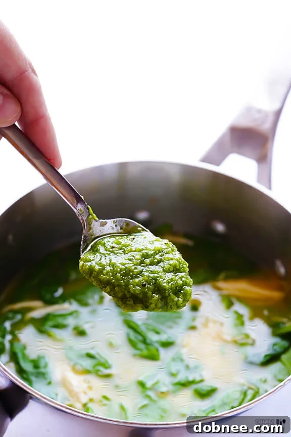 Ingredients for 5-Ingredient Pesto Chicken Soup simmering in a saucepan.