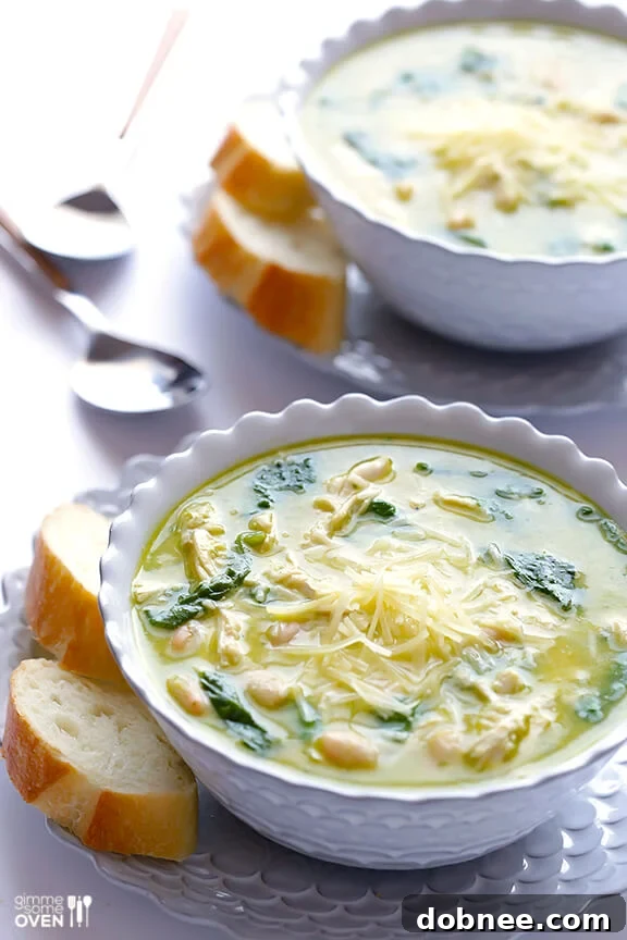 Close-up of a spoon scooping 5-Ingredient Pesto Chicken Soup, topped with Parmesan and fresh basil.