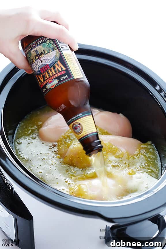 Beer being added to a slow cooker with chicken and salsa verde