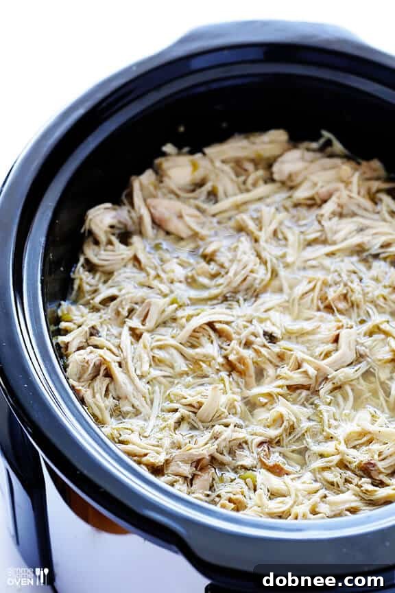 Shredded Salsa Verde Chicken mixed with juices in slow cooker