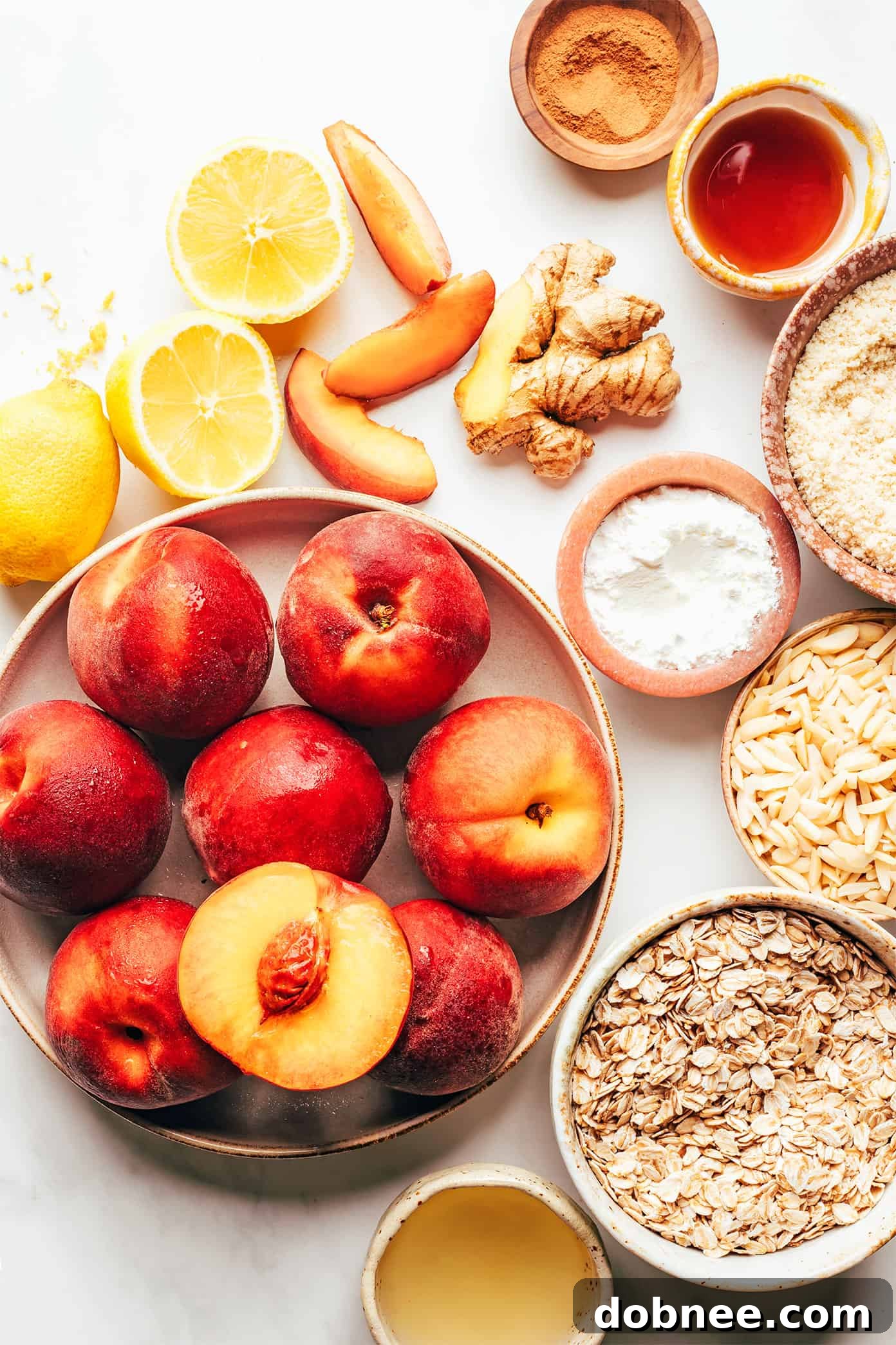 Close-up of fresh ingredients for Ginger Peach Crisp, including ripe peaches, ginger, lemon, oats, and almonds.