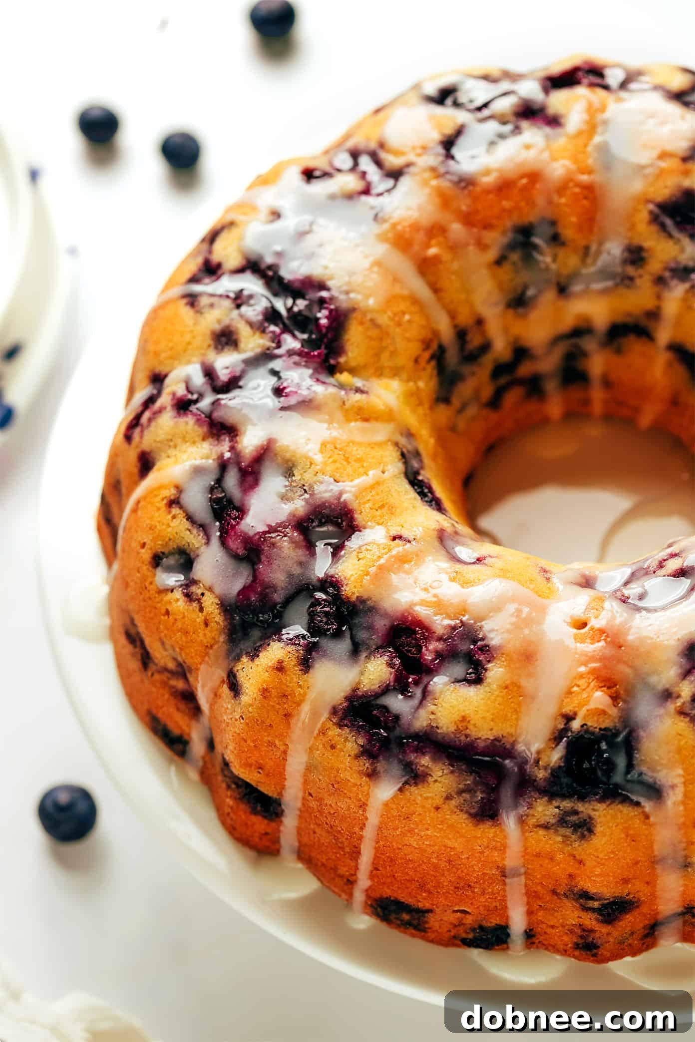 A stunning baked blueberry bundt cake, perfectly golden brown, sitting on a wire rack cooling, with a rich glaze drizzled over it.