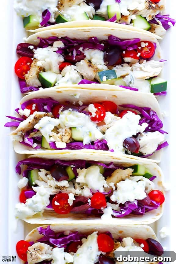 Close-up of Greek Fish Tacos with colorful toppings.