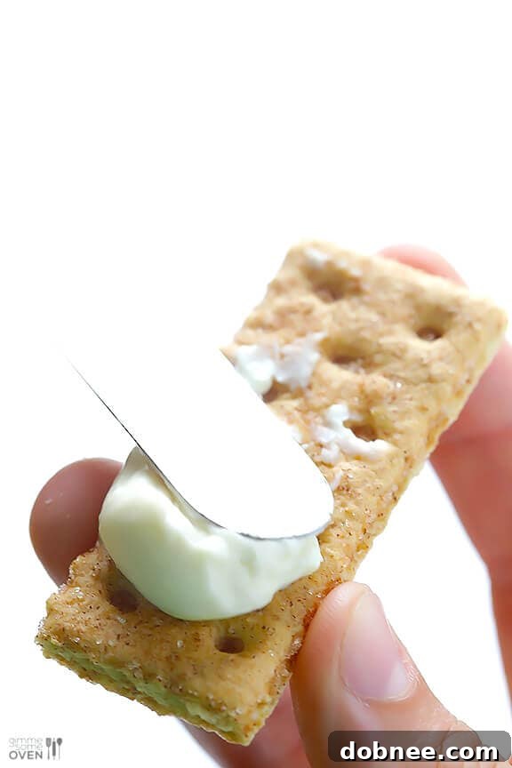 Spreading Laughing Cow cheese on a graham cracker for blueberry cheesecake bites.