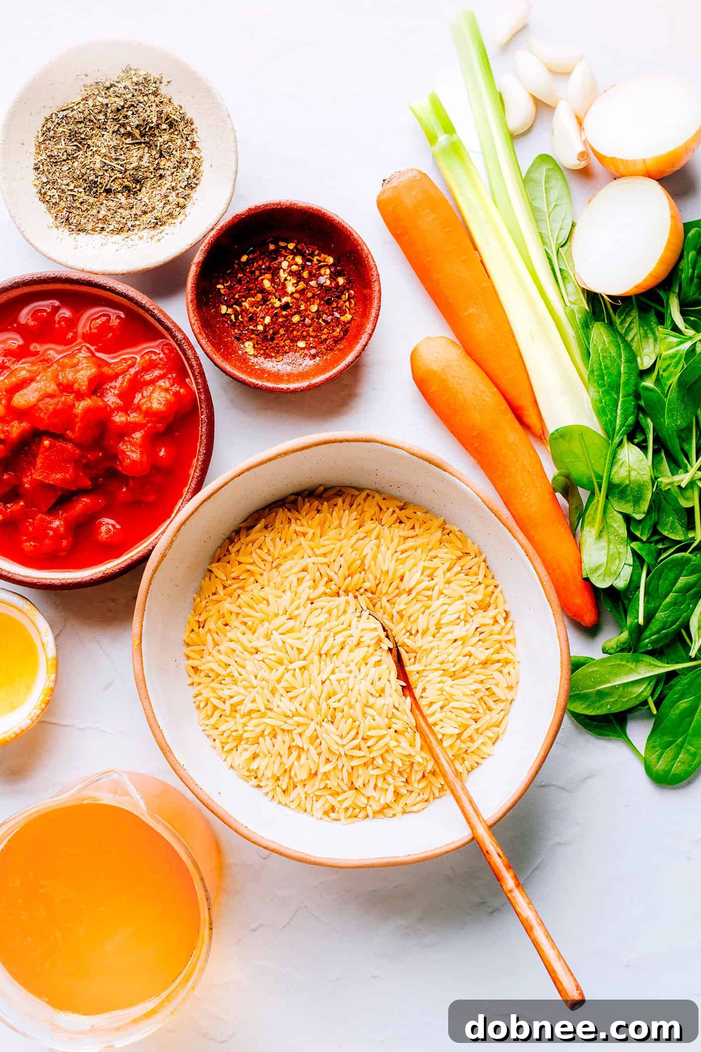 A collection of fresh ingredients laid out for Italian Orzo Spinach Soup preparation