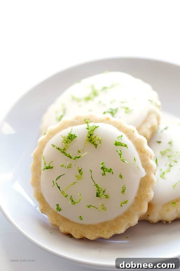 A tray of Coconut Lime Shortbread Cookies, some with lime zest mixed into the glaze, others with zest sprinkled on top, offering different presentation styles.