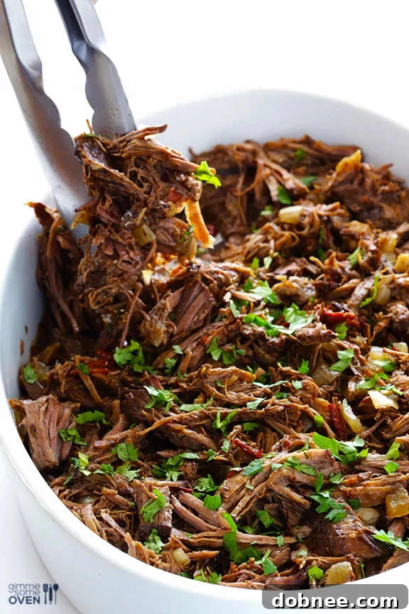 Shredded barbacoa beef simmering in its juices in the slow cooker.