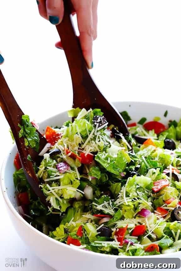 Hands tossing Pepperoni Italian Chopped Salad with red wine vinaigrette