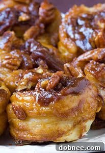 A plate of freshly baked easy sticky buns, drizzled with caramel and sprinkled with pecans.