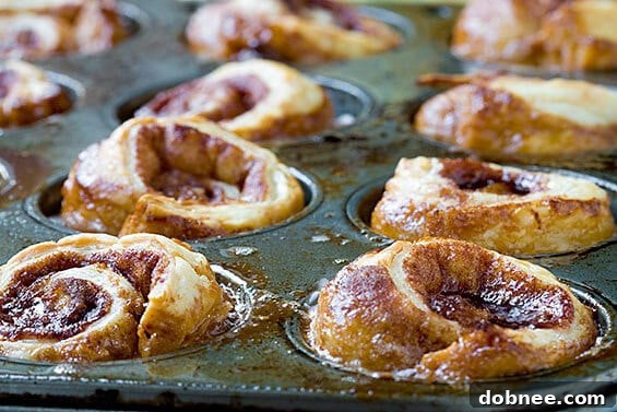Three perfectly baked sticky buns arranged on a white plate, showcasing their inviting golden color and gooey texture.