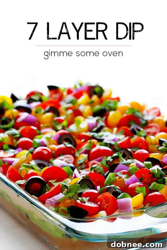 A large serving of 7 Layer Dip with tortilla chips, ready for a party.