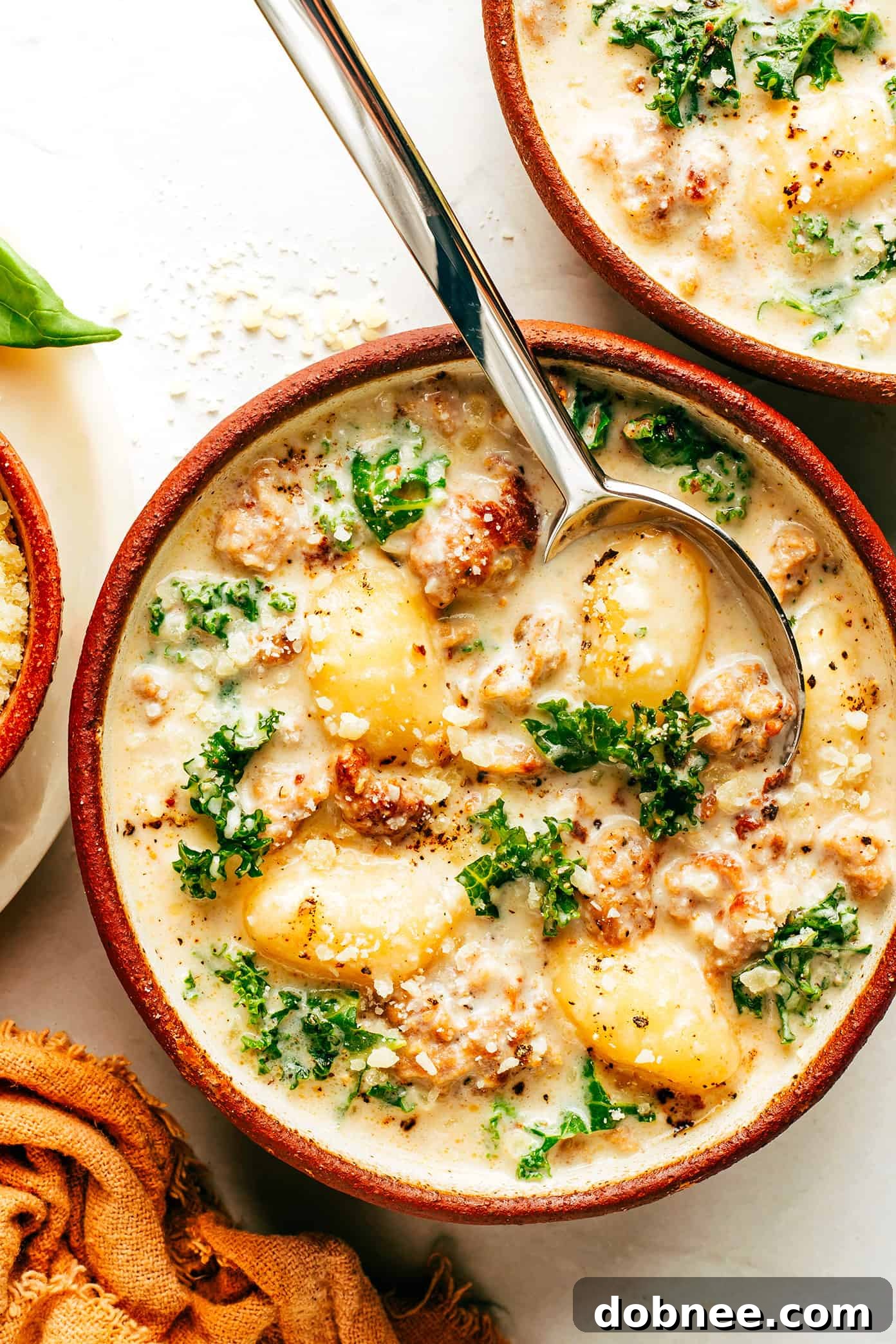 A close-up of a rustic bowl of homemade Zuppa Toscana with gnocchi, ready to be enjoyed, garnished with Parmesan.