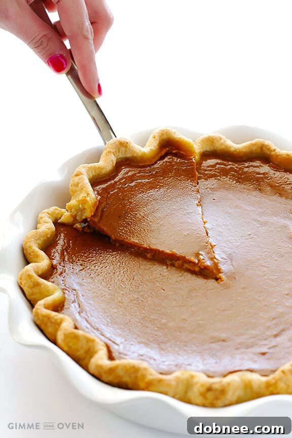 A close-up of a generous slice of Bourbon Pumpkin Pie, adorned with a dollop of bourbon whipped cream, ready for the first delectable bite.