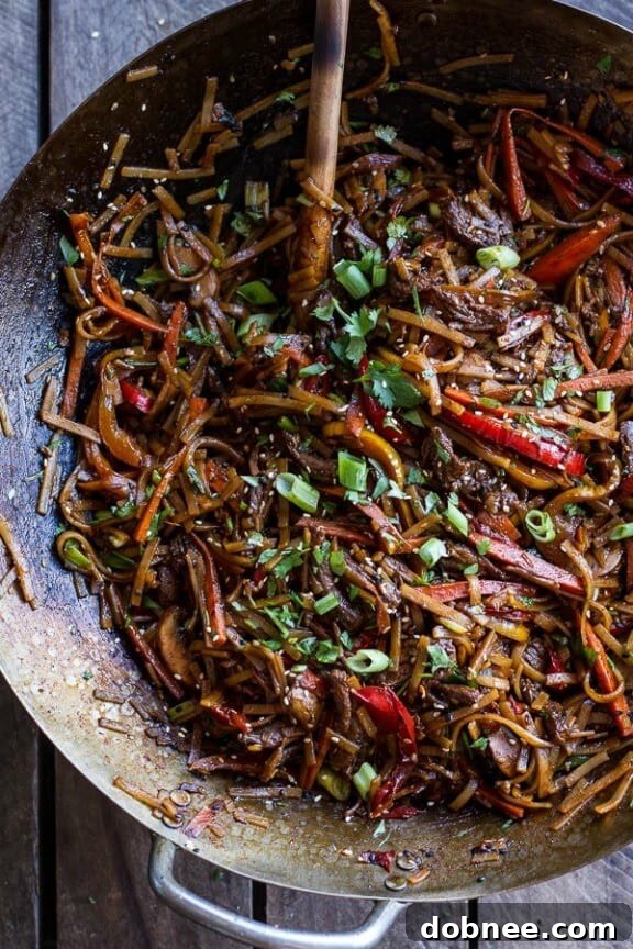 A savory bowl of stir-fried Korean beef and toasted sesame noodles, garnished with fresh herbs and sesame seeds.