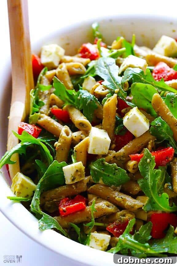 A refreshing and easy 5-ingredient pesto pasta salad, garnished with cherry tomatoes and basil.