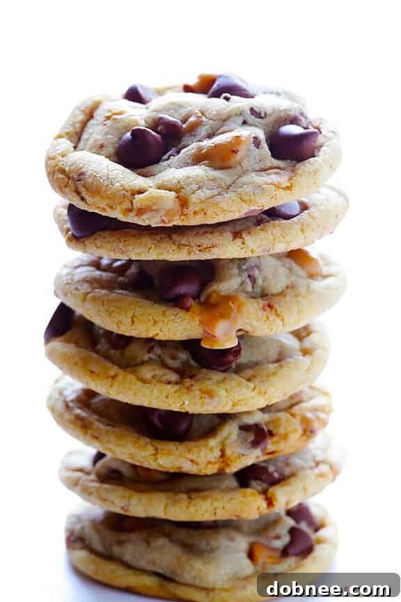 A close-up of a single Toffee Chocolate Chip Cookie with melted chocolate and golden toffee bits visible.