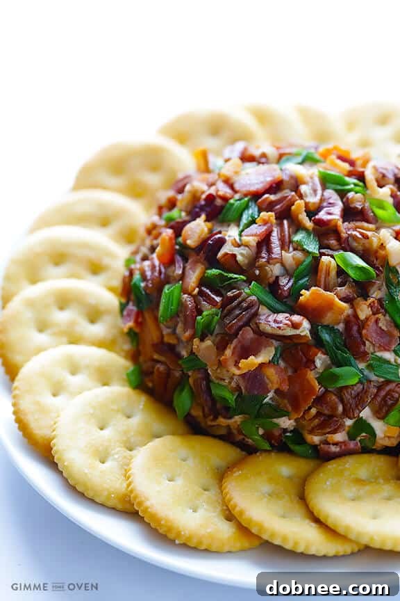 Bacon BBQ Cheese Bomb 6 The BBQ Bacon Cheese Ball being rolled in a savory coating of bacon, green onions, and pecans.