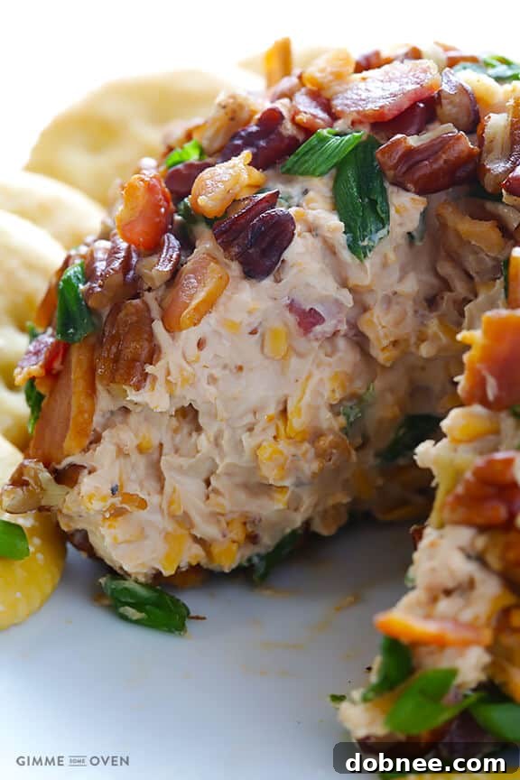 Bacon BBQ Cheese Bomb 7 A close-up of the BBQ Bacon Cheese Ball, showing a portion scooped out with a cracker, revealing its creamy, flavorful interior.