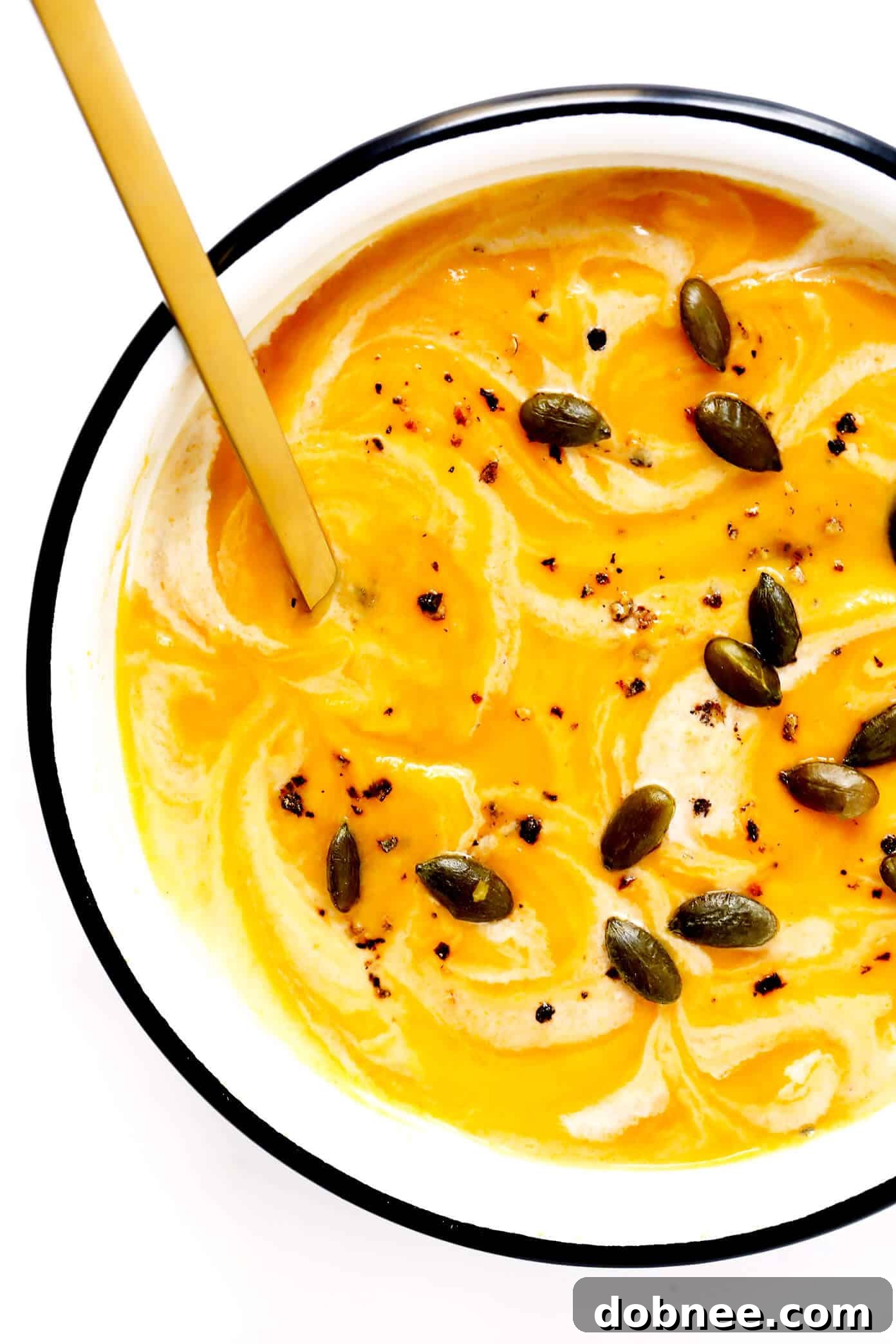 A bowl of creamy Vegan Butternut Squash Soup topped with toasted pepitas.