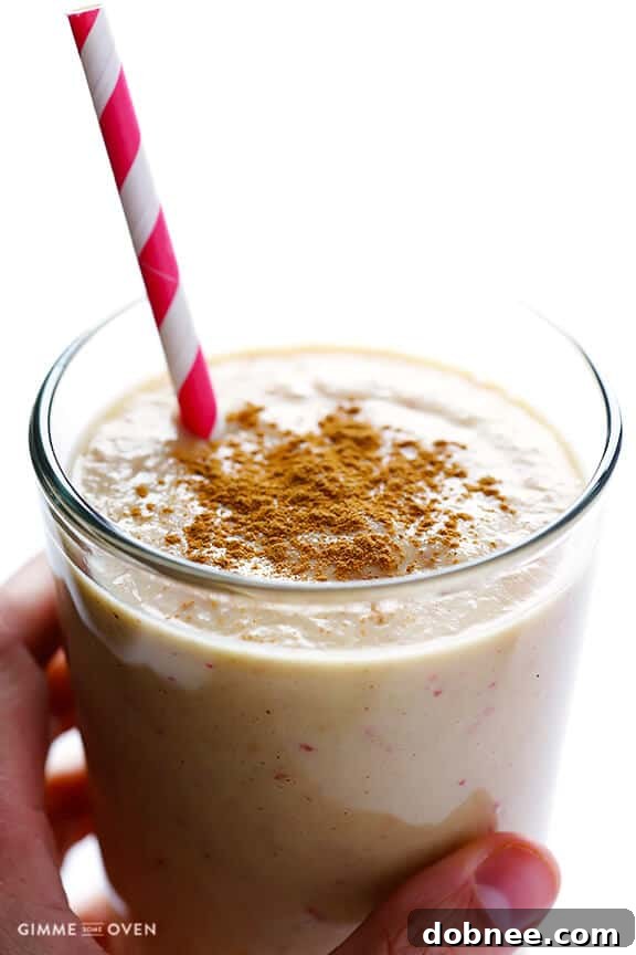 Close-up shot of the Apple Pie Protein Smoothie, showing its thick and creamy texture, with hints of cinnamon. The glass is sitting on a wooden surface, evoking a rustic, cozy feel.