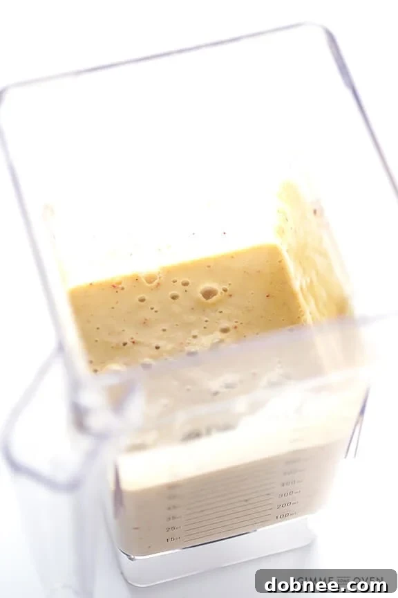 A blender being filled with the various ingredients for the Apple Pie Protein Smoothie, including chopped apples, frozen banana, Greek yogurt, and almond milk, highlighting the easy preparation process.