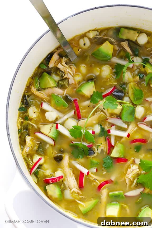 A vibrant bowl of Easy Chicken Posole Verde, garnished with fresh toppings.