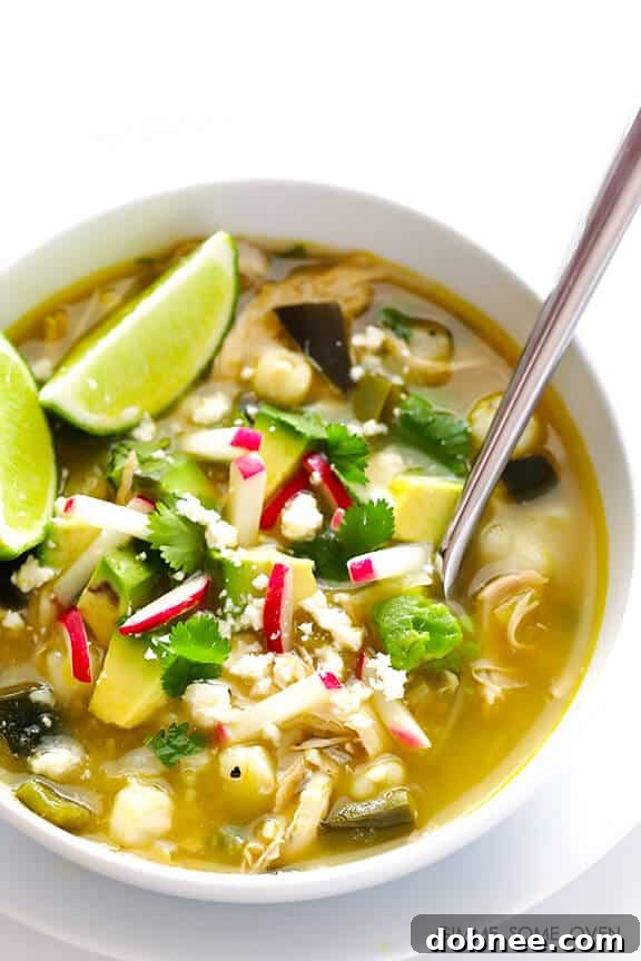 Easy Chicken Posole Verde ready to be served, garnished with fresh avocado and cilantro.