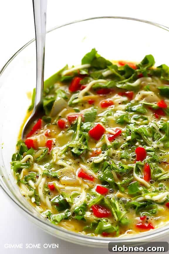 A closer look at the fresh baby arugula being added to the frittata mixture for vibrant color and flavor.