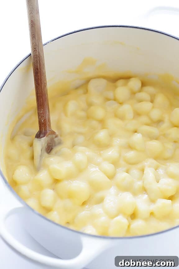 Gnocchi being tossed with the creamy cheese sauce in a pot