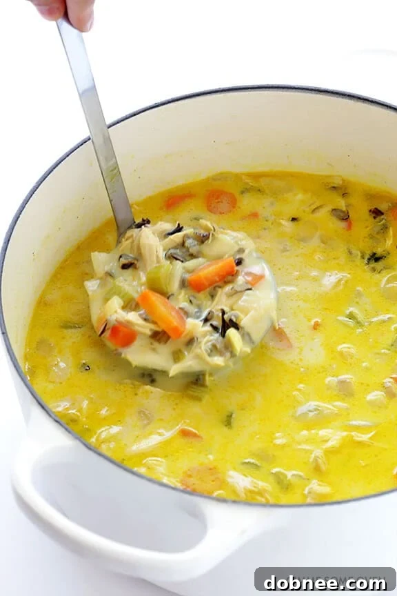 A golden-hued Curried Chicken and Wild Rice Soup presented beautifully in a white bowl, ready for a comforting meal.
