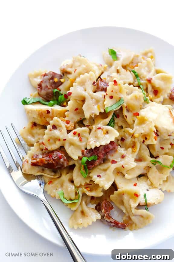A close-up of a plate of Creamy Pasta with Chicken & Sun-Dried Tomatoes, showing the rich sauce and vibrant ingredients