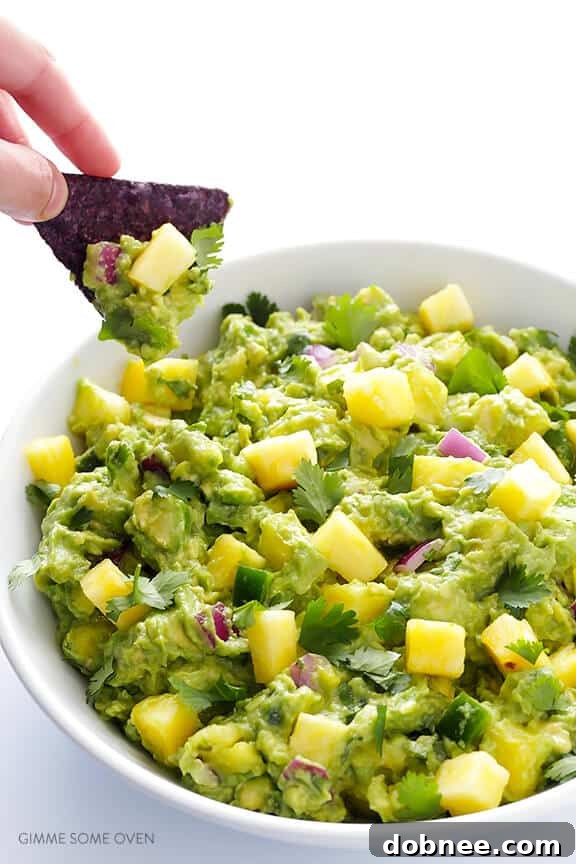 Freshly made pineapple guacamole served in a rustic bowl with blue corn tortilla chips, garnished with extra pineapple and cilantro.