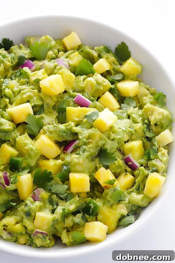 Close-up shot of creamy pineapple guacamole in a serving bowl, showcasing chunks of avocado and golden pineapple.