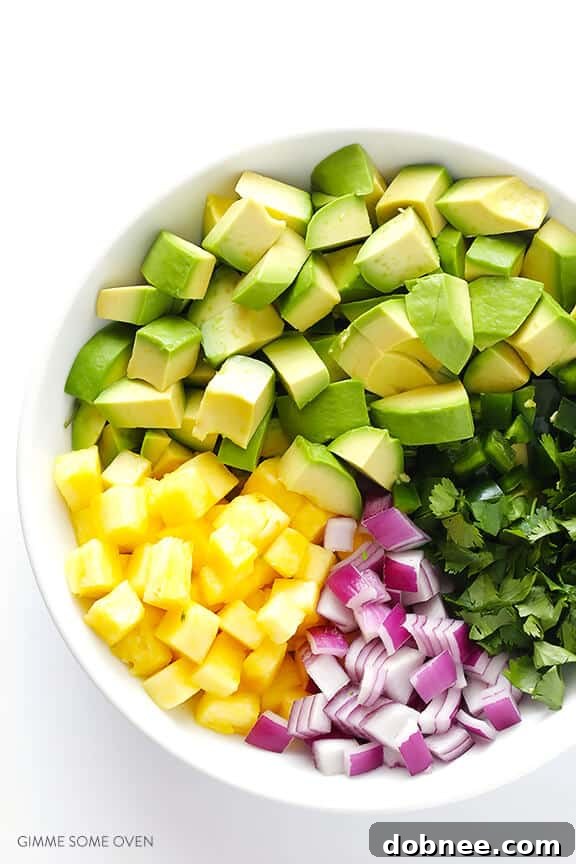 Overhead shot of diced ingredients for pineapple guacamole, including avocado, red onion, jalapeño, cilantro, and fresh pineapple.